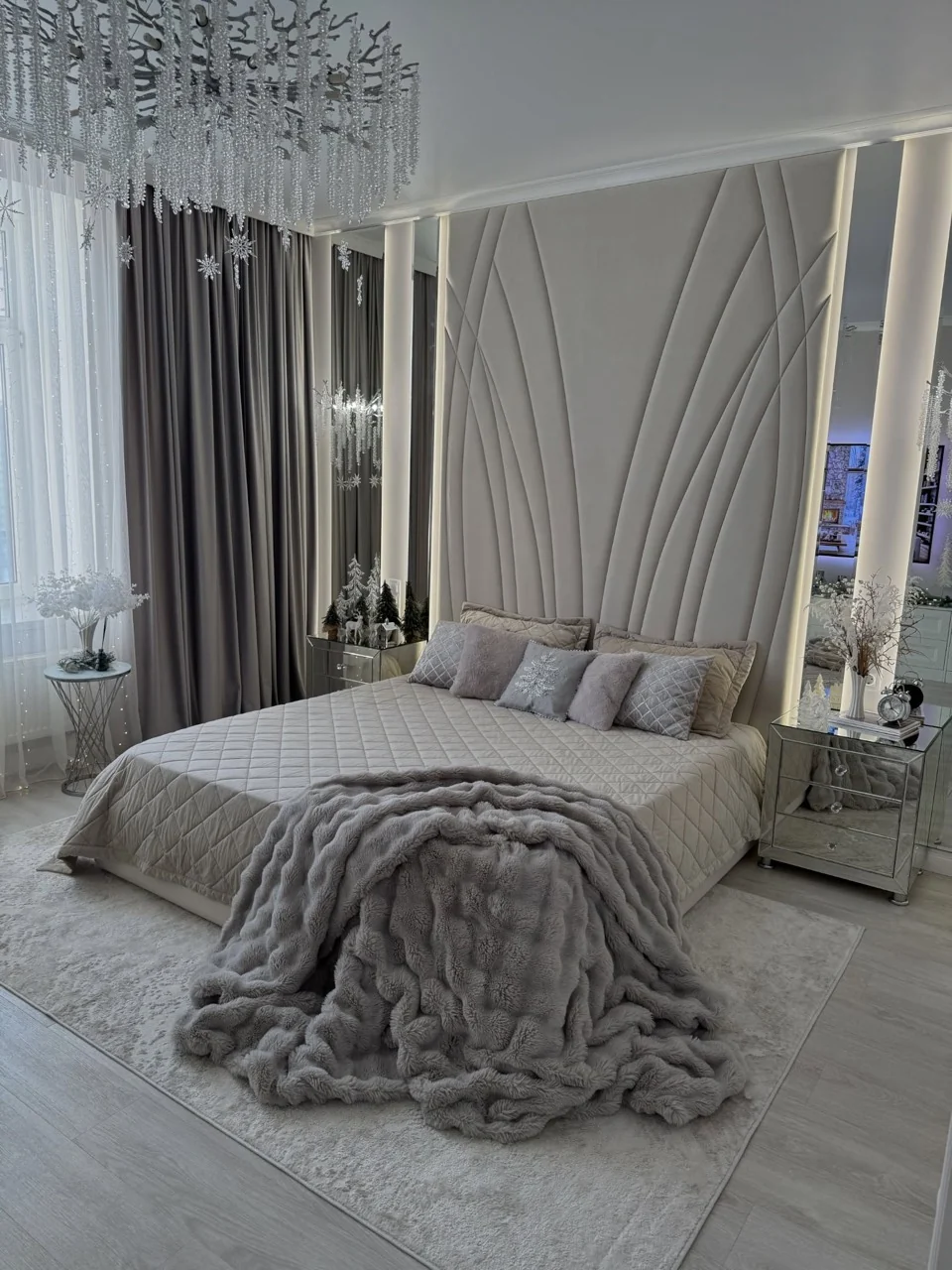 Grey and white bedroom with a textured throw, mirrored bedside cabinets and small winter decorations.