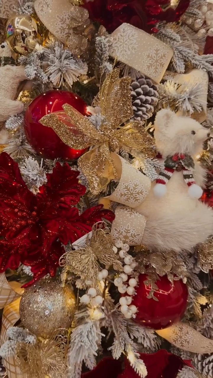 Red, white and gold ornaments, patterned ribbon and winter figures on a Christmas tree.