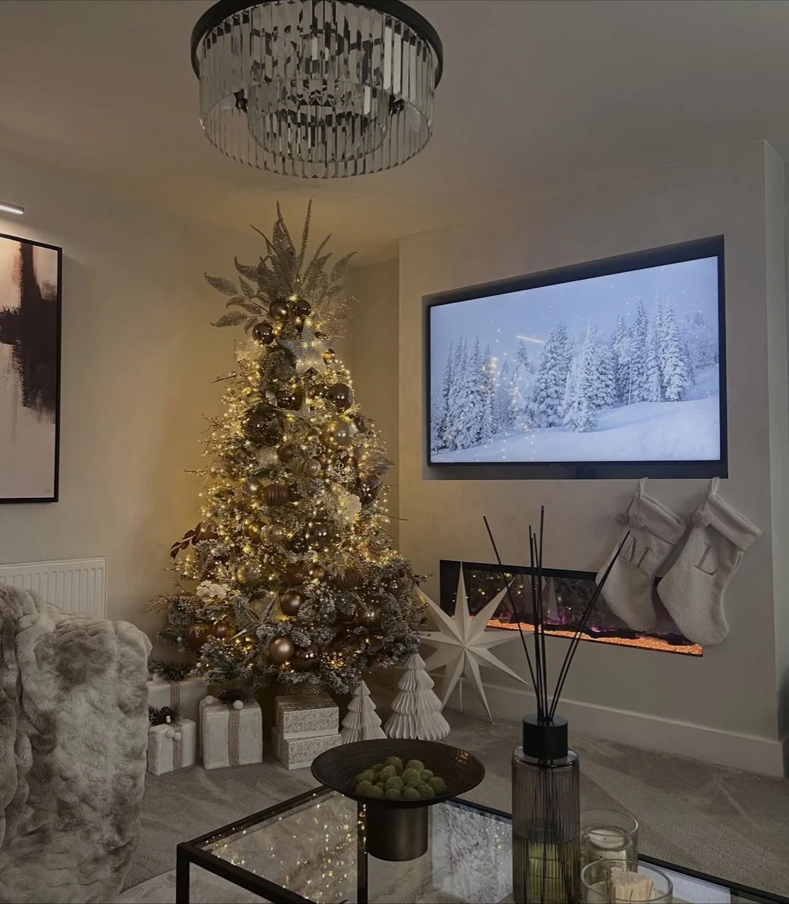 Bronze and gold Christmas tree glowing beside a fireplace and wrapped gifts.