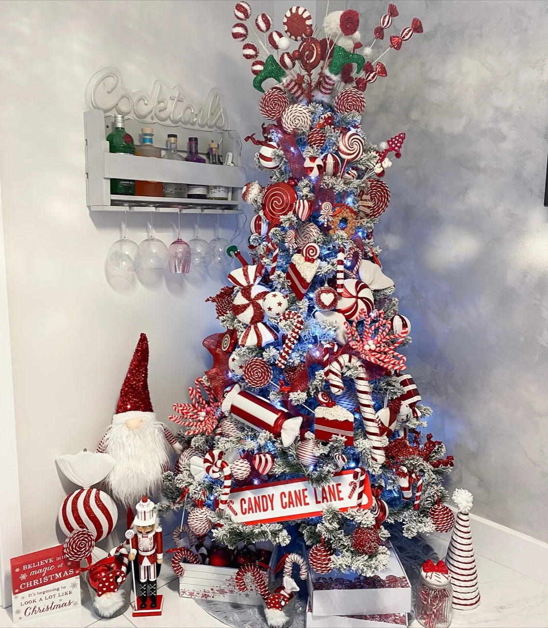 Red and white candy-cane Christmas tree with peppermint ornaments, a Candy Cane Lane sign, nutcracker and festive figures.